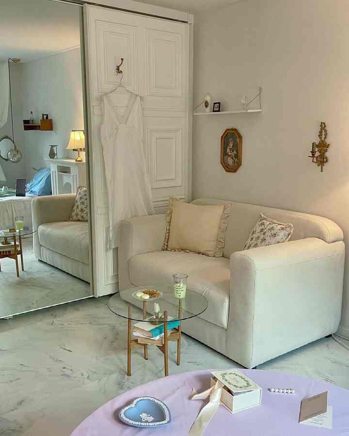 White and beige toned living room featuring a two-seater sofa and glass-top side table with simple modern decor