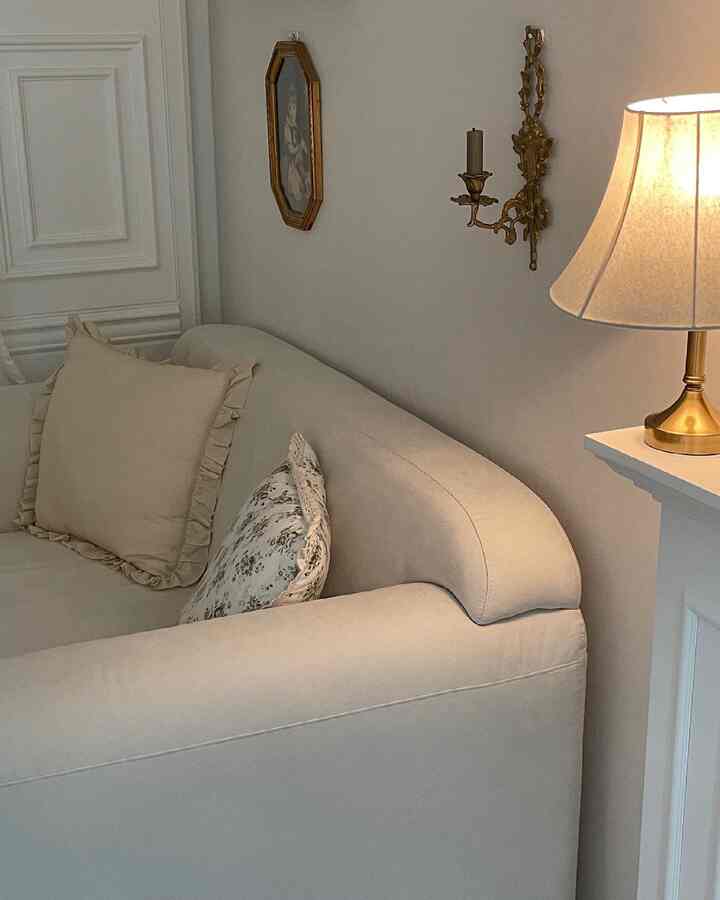 Cream-toned living room featuring a cream sofa, cushions, vintage candleholder and picture frame creating a cozy ambiance