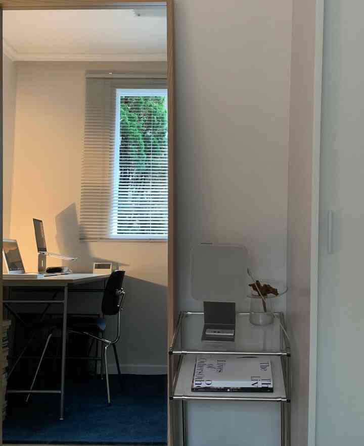 A small home office space in white and blue tones featuring a desk, chair, and blinds with minimalist design
