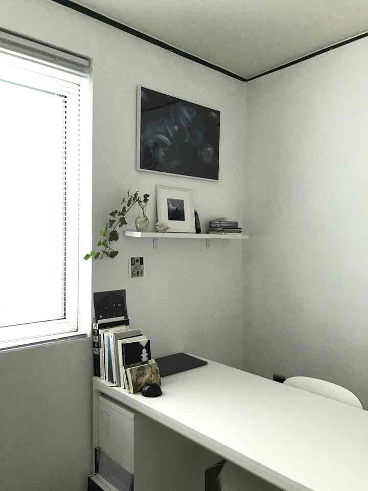 Bright white toned home office space featuring a simple desk and shelf with a clean workspace atmosphere