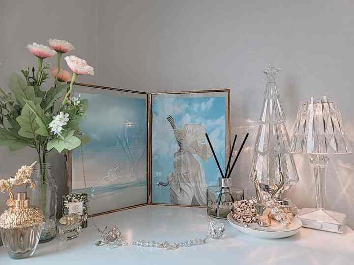 明るいホワイトのテーブルにゴールドフレームの額縁、ブルーの絵画、クリスタル照明が配置された洗練されたキラキラとしたインテリア空間