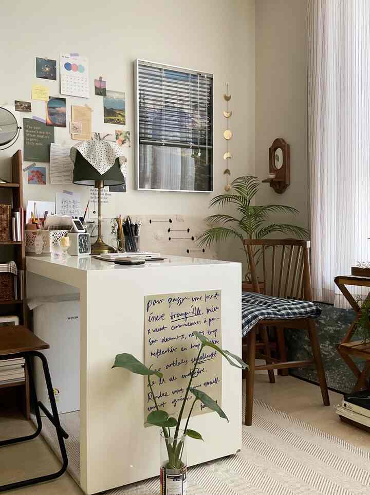 ホワイトと木目調のワンルーム、植物とポスターが配置されたモダンなホームオフィスの空間