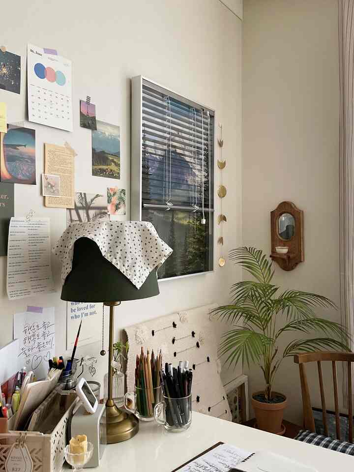 A compact home office space in white and green tones, featuring a table lamp and plant providing a cozy work area