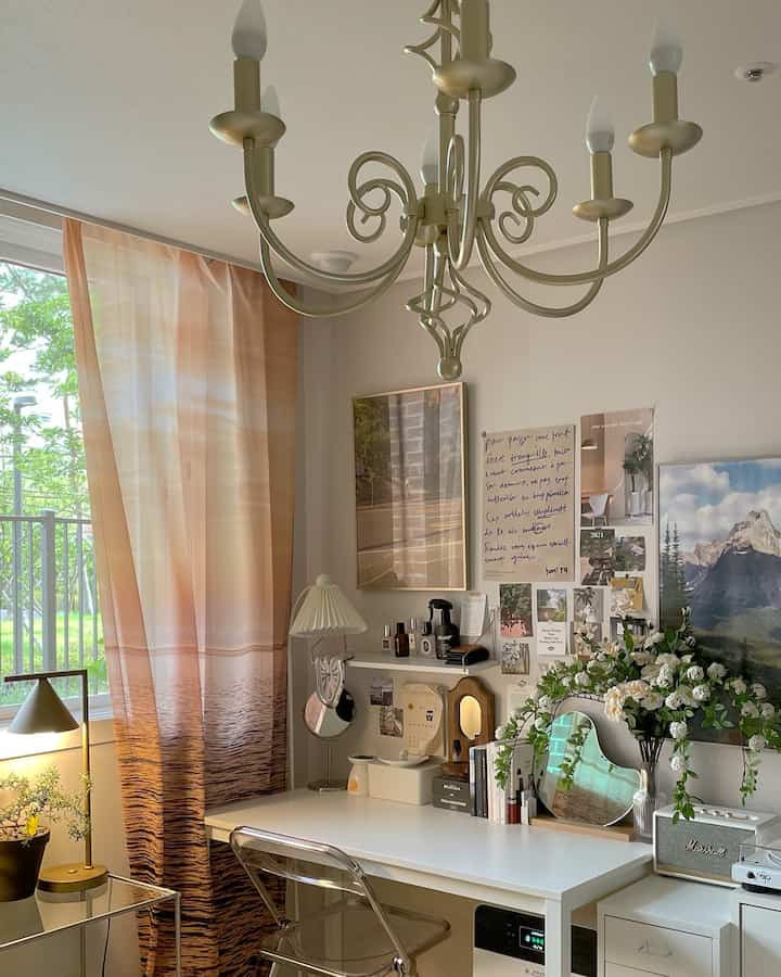 柔らかいベージュと白の色調のワンルーム、整頓されたデスクと花の飾り、ポスターが調和した雰囲気のあるホームオフィス空間