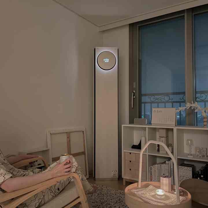 Beige and white tone living room featuring LG Whisen tower air conditioner, armchair, and candle, creating a calm atmosphere