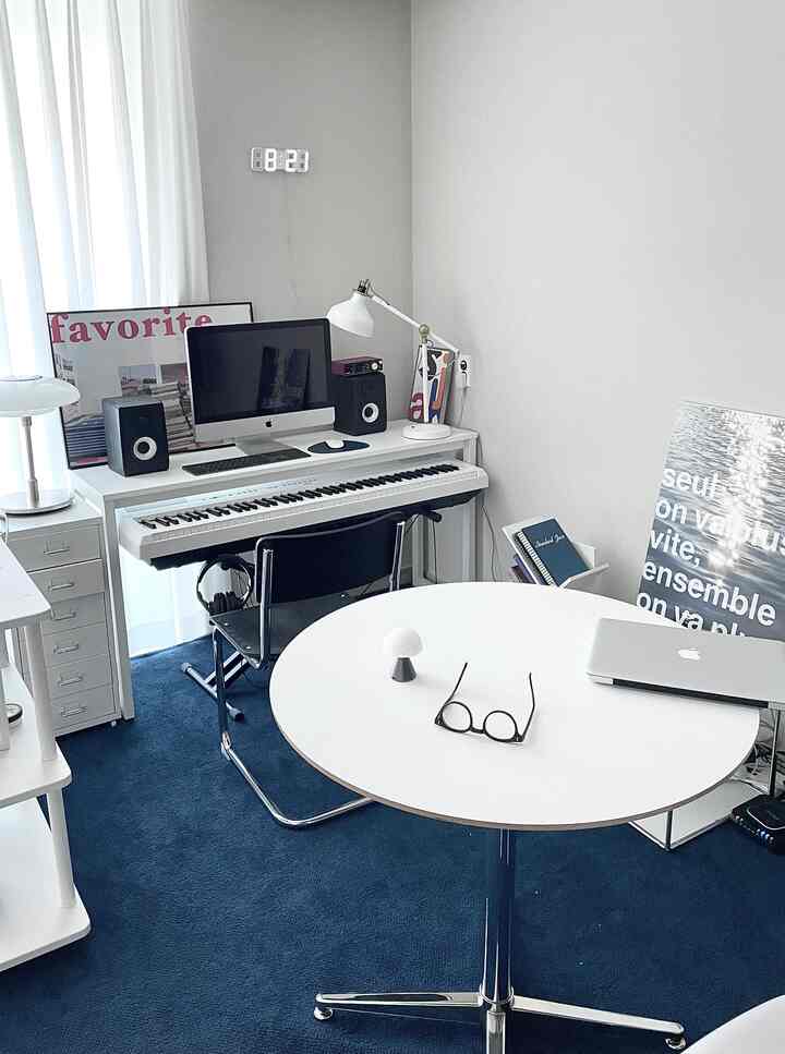 White and blue toned studio living room and home office featuring a white round table and Nomia blue rug, simple calm atmosphere