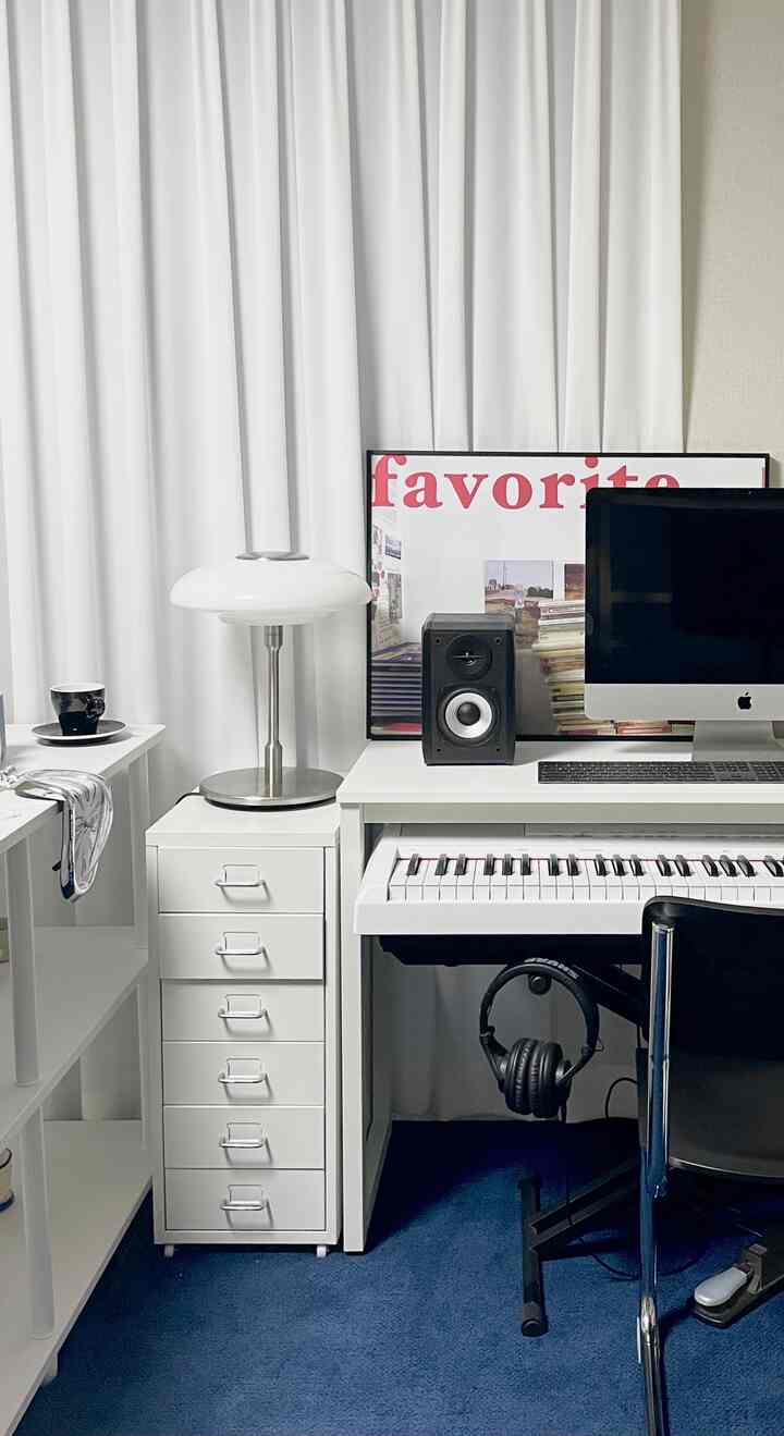 White curtains and desk in a studio apartment home office, featuring MIDI keyboard and iMac in a harmonious music workspace