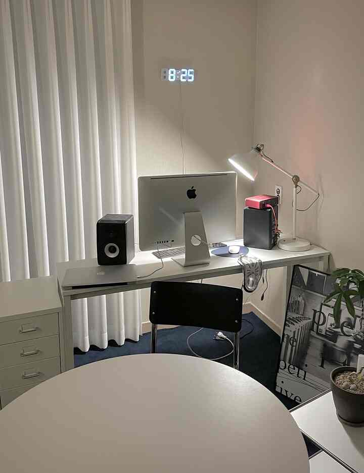 Modern home office in white and black tones featuring a desk and floor lamp in a compact room layout