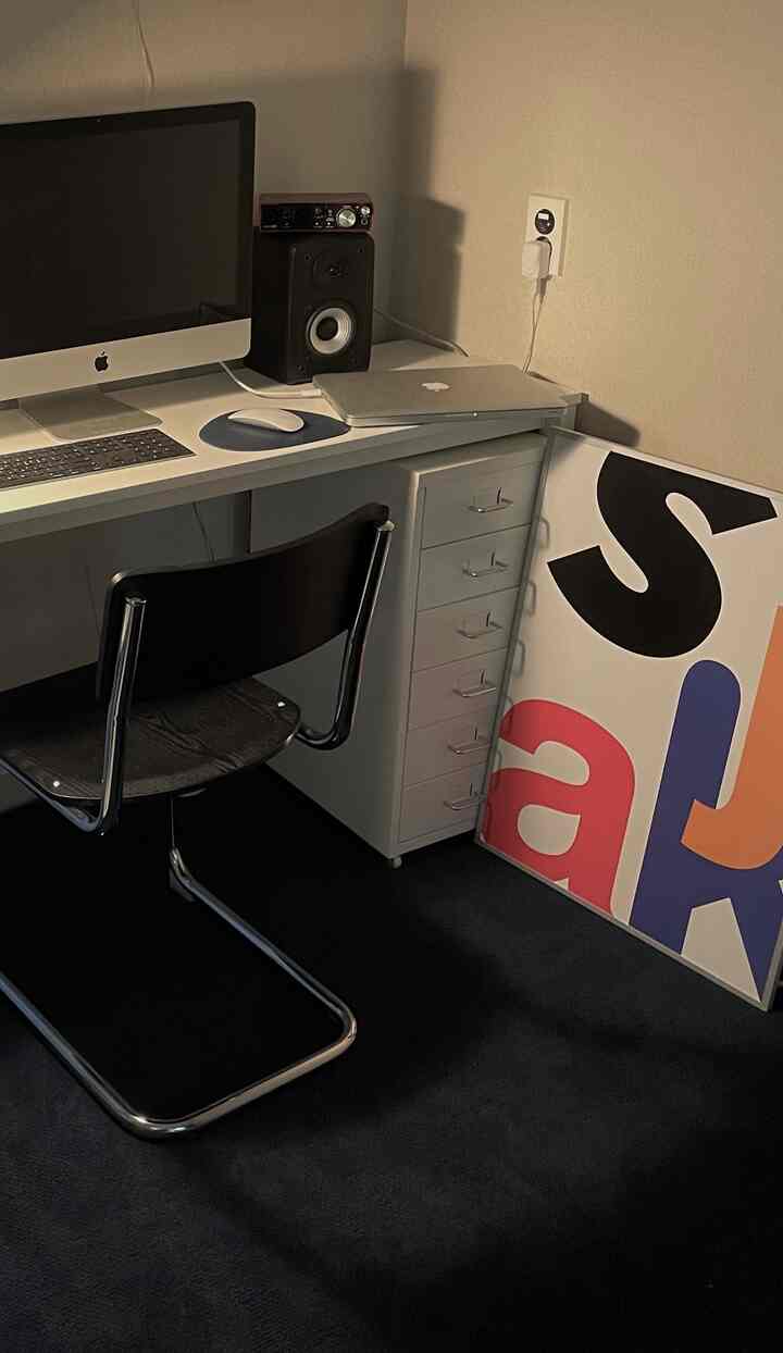 A softly lit modern home office for one featuring a white desk and black rug