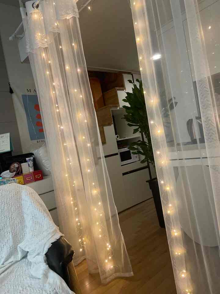 ホワイトとナチュラルカラーのリビング、ストリングライトとカーテンが温かみのある雰囲気を演出