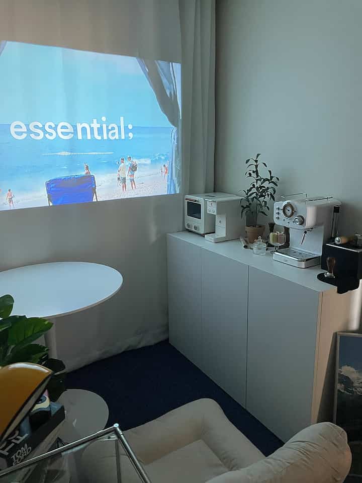 ホワイトとブルーの色調でまとめられた小さなホームカフェ空間、コーヒーマシンとミニオーブントースター、キャビネットが配置された落ち着いた雰囲気のインテリア