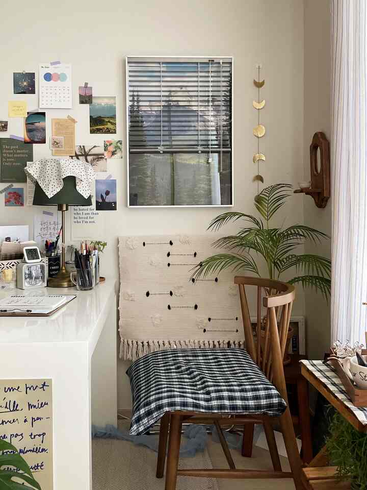 ナチュラルな色調のホームオフィス、木製の椅子とデスク、緑の植物が配置された雰囲気のある作業空間