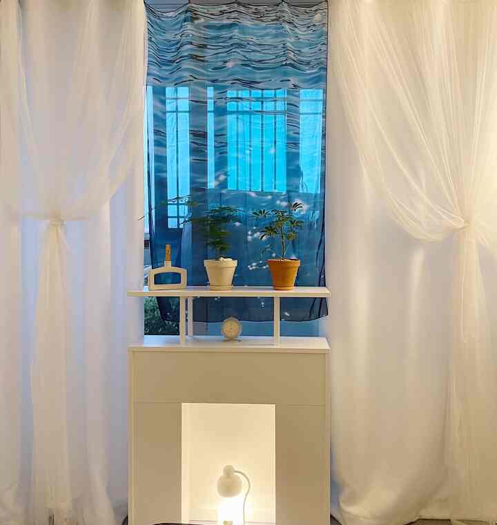 White and blue veranda space featuring plants and curtains creating a clean, bright atmosphere