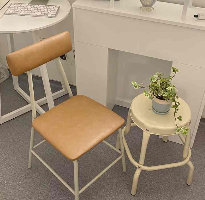 White and brown toned compact home office space featuring a stool, chair, and potted plant with a clean interior