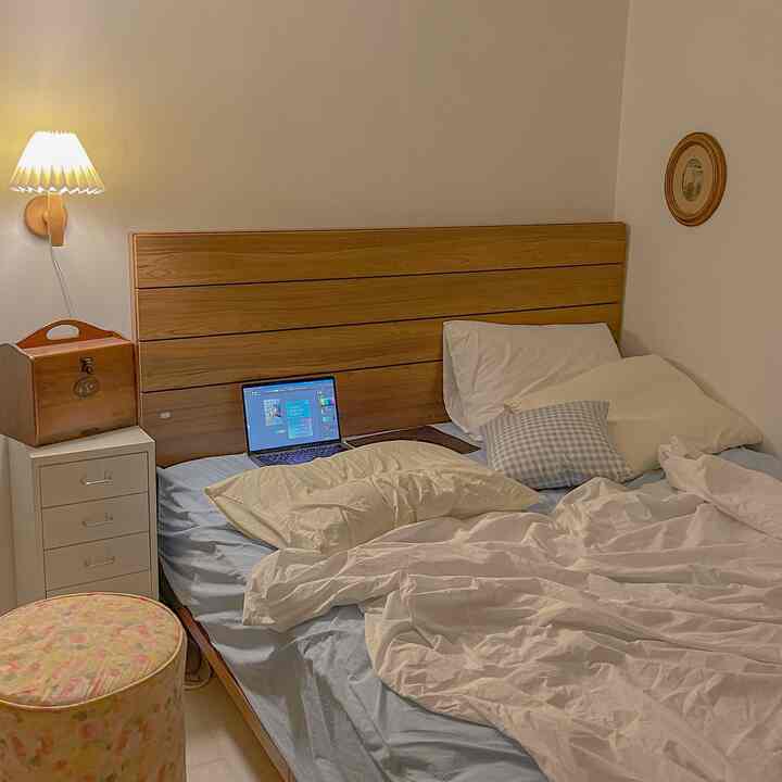 White and wood tone bedroom featuring bed, dresser, and stool in a cozy, natural atmosphere