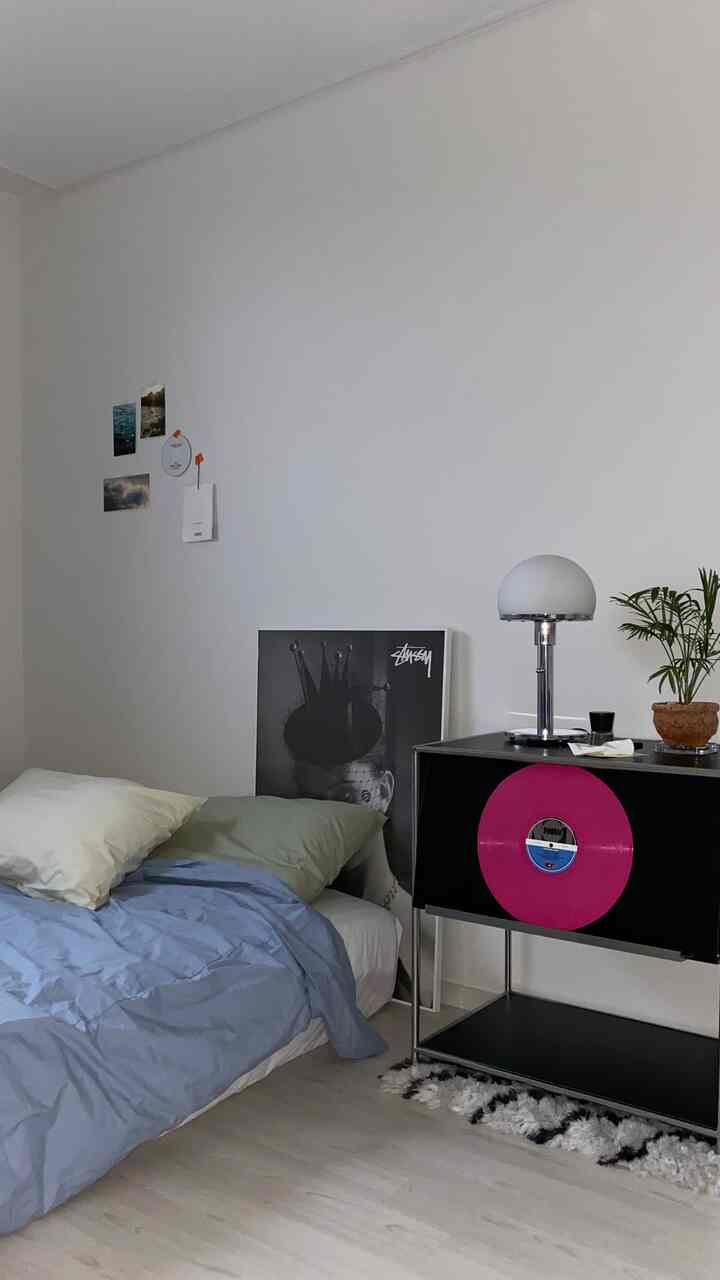 Monotone 6-tatami bedroom with white walls featuring a bed, table lamp, plant, creating a simple and modern atmosphere