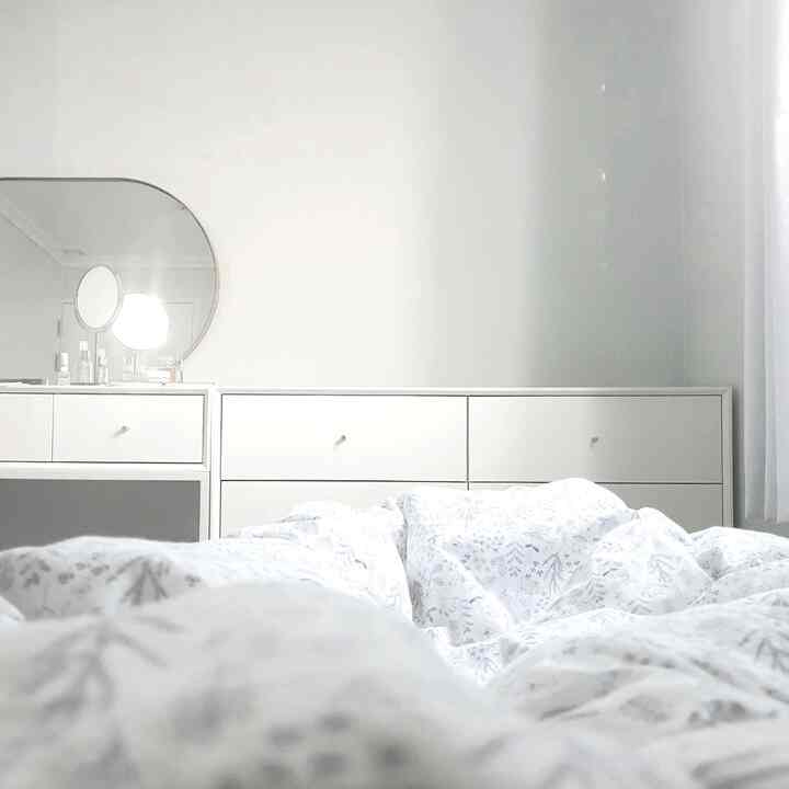 白を基調とした寝室、化粧台とチェストが配置されたシンプルでミニマルな雰囲気のインテリア