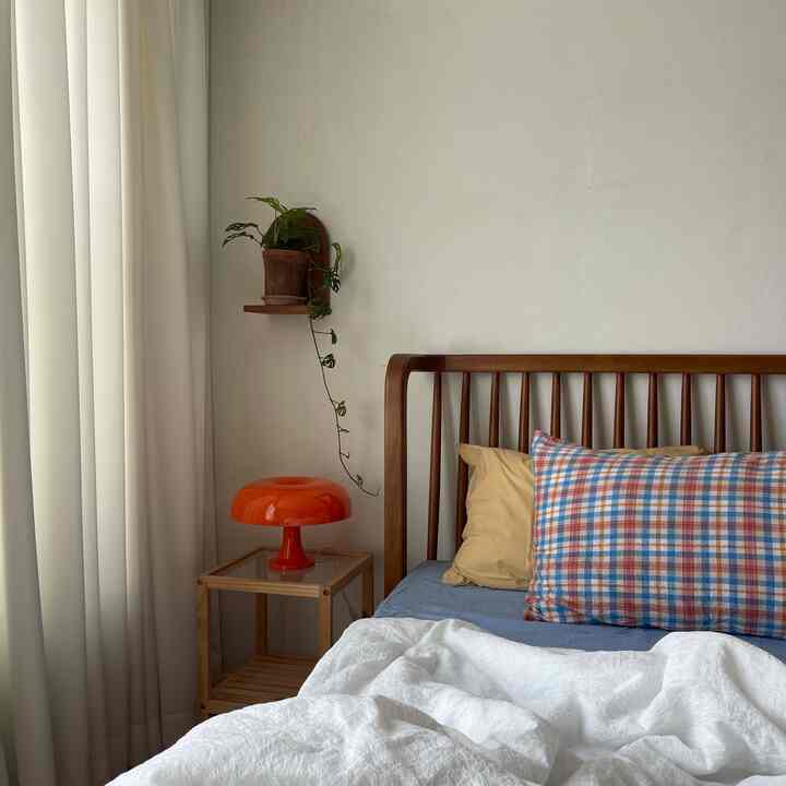 White and wood-tone bedroom featuring a wooden bed frame and an orange table lamp, creating a natural modern atmosphere