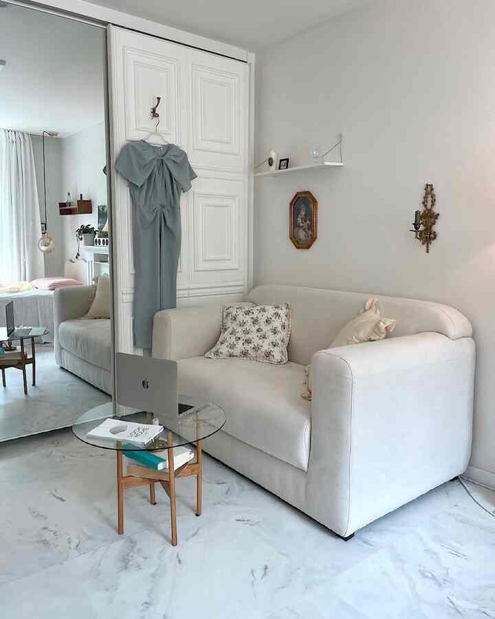 Bright white and natural tone living room featuring a two-seater sofa and glass side table in a clean, modern space