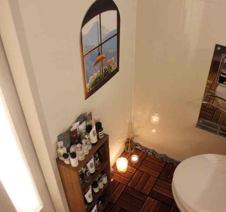 木目調の床とポスターが配置されたバスルーム、キャンドルとディフューザーで温かみのある雰囲気のあるインテリア