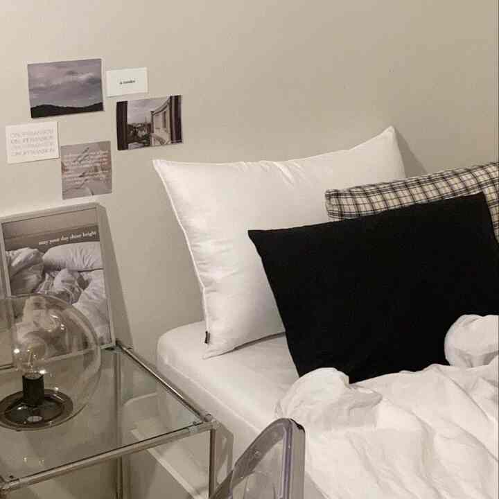 White and black toned bedroom featuring transparent nightstand and posters with a modern atmosphere
