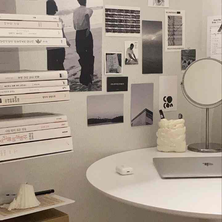 White-toned home office study space featuring a round desk and bookshelf with a minimalist interior