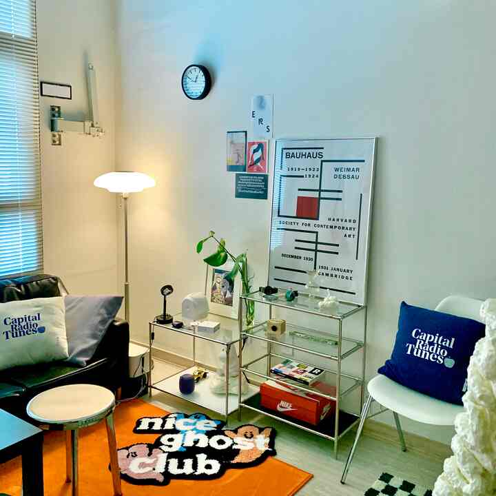 White and black toned living room featuring mid-century modern sofa, transparent glass shelves, and a striking Bauhaus poster