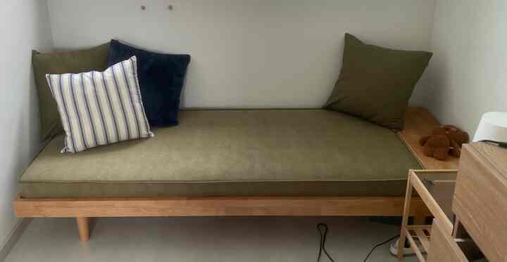 ナチュラルトーンの小さな書斎空間、木製のデイベッドにクッションや小物が配置されたくつろげるインテリア