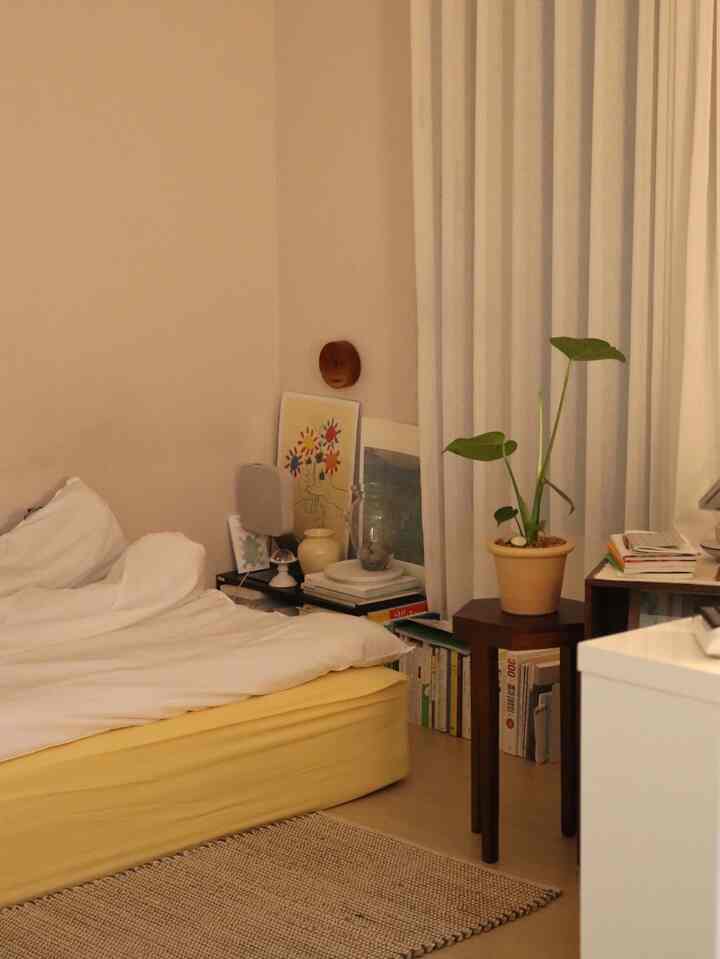 Warm beige and yellow toned bedroom featuring a bed, wooden side table, and green plant, creating a calm atmosphere