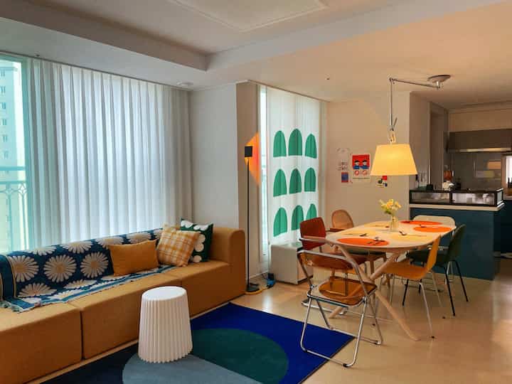 Natural beige and mustard toned living and dining room featuring vintage style sofa and dining chairs, creating a cozy atmosphere