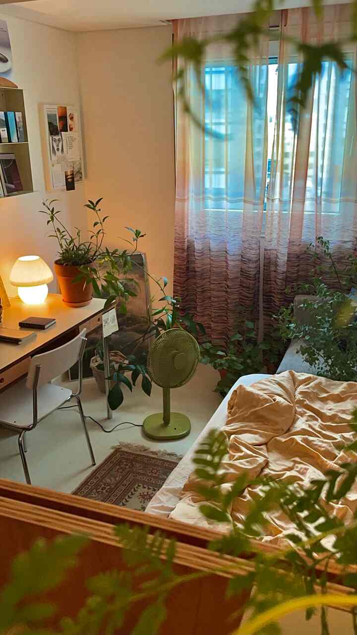 Natural-toned bedroom featuring a desk and abundant plants with a cozy atmosphere