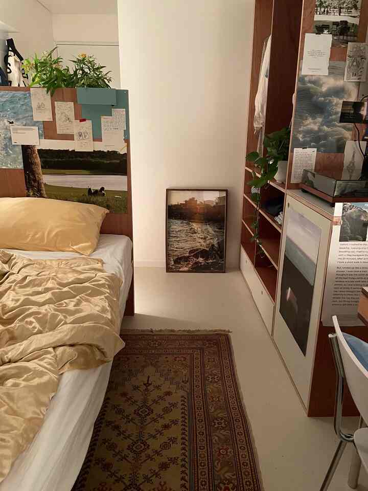 Cozy small bedroom featuring beige and wood tones, adorned with Persian carpet and sea poster creating a warm atmosphere