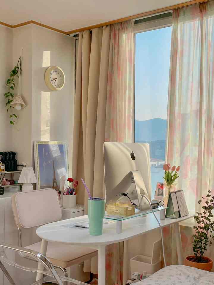 Natural tone studio home office with white desk and beige curtains, featuring computer and chair in a warm cozy atmosphere