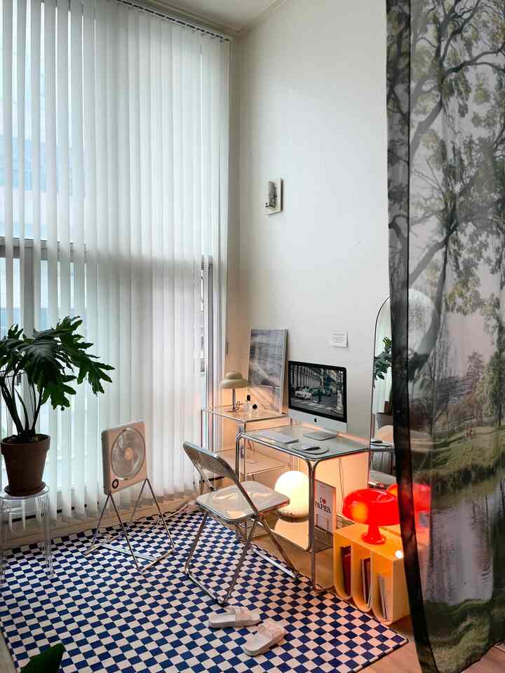 ホワイトとクローム色調のワンルームホームオフィス、チェッカーボードラグと透明家具が配置されたシンプルな作業空間