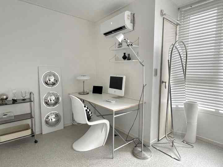 Monotone white studio apartment home office featuring a simple modern desk and chair in a clean, quiet workspace