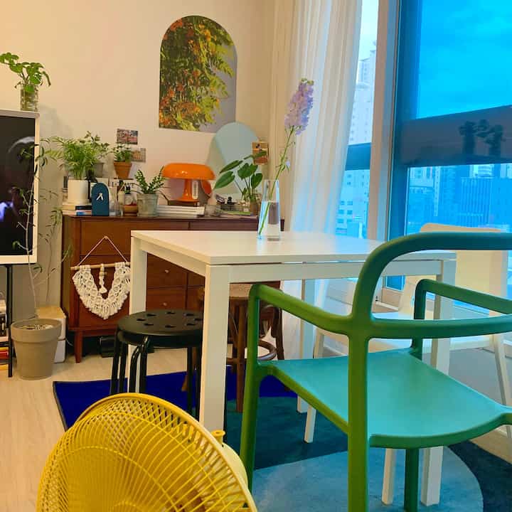 White and green toned dining room featuring diverse chairs and plants with a modern vintage atmosphere