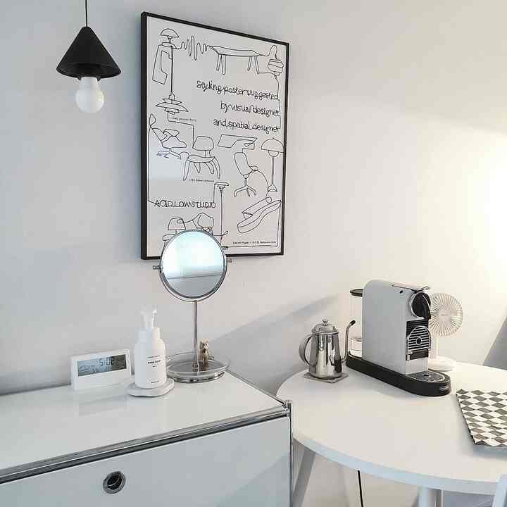 White-toned kitchen space featuring a Mid-Century Modern style poster and a coffee machine, creating a clean home cafe interior