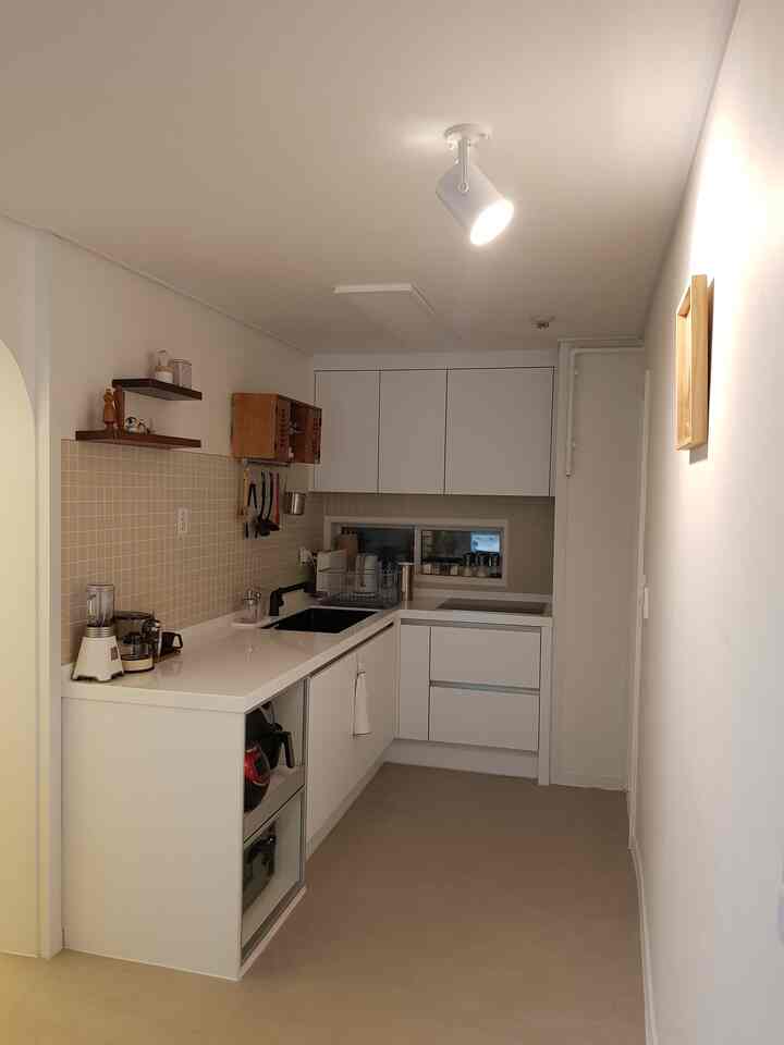 White and natural-toned compact kitchen without upper cabinets, featuring modern and clean layout