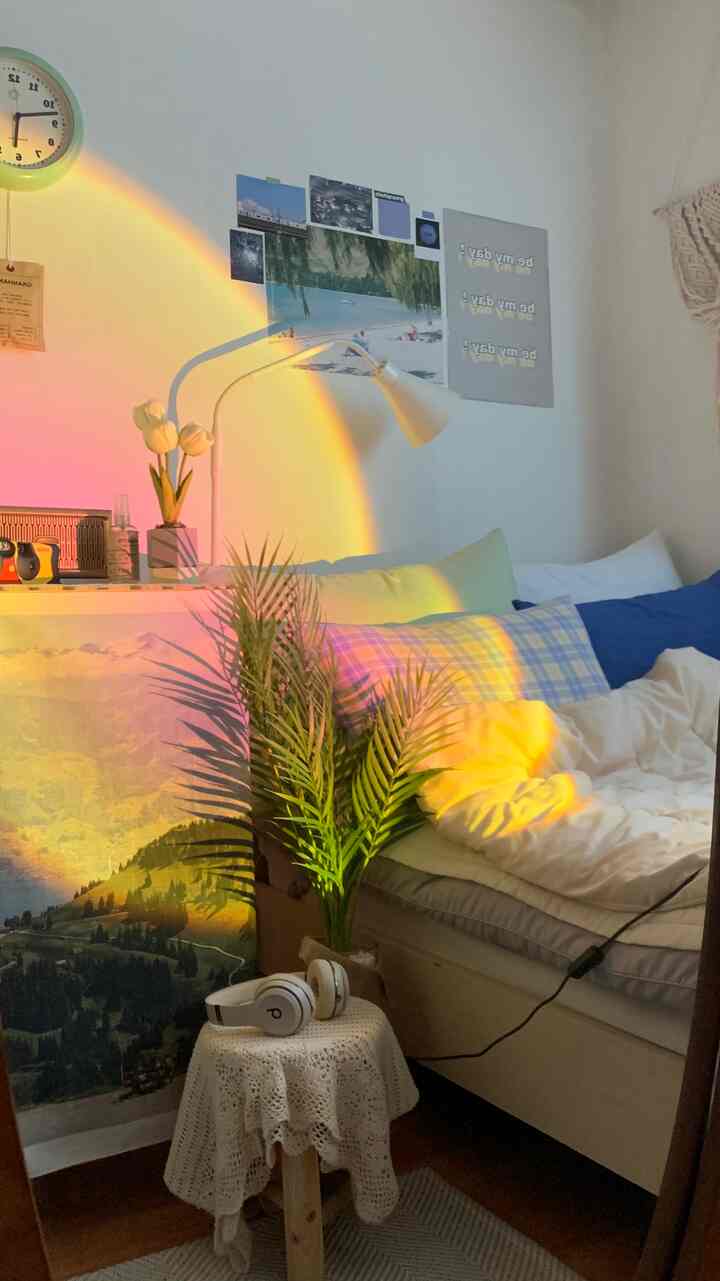Bedroom with warm yellow and green lighting, featuring artificial areca palm and assorted pillows creating a cozy atmosphere