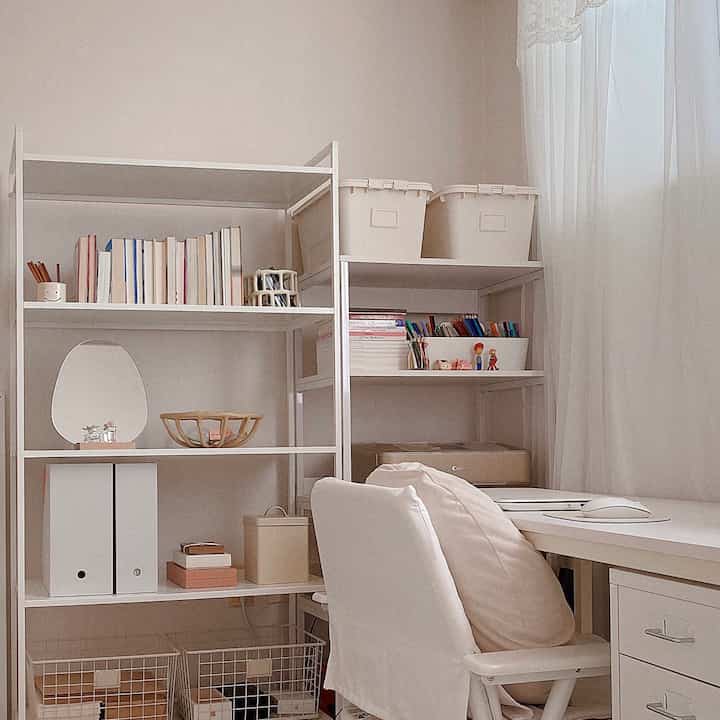 A small home office space in white and beige tones featuring a tidy desk and shelves creating a harmonious atmosphere