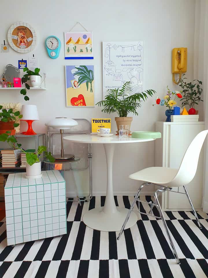 White and red toned dining room featuring a round dining table, dining chair, wall frames, and plants in a simple modern setting