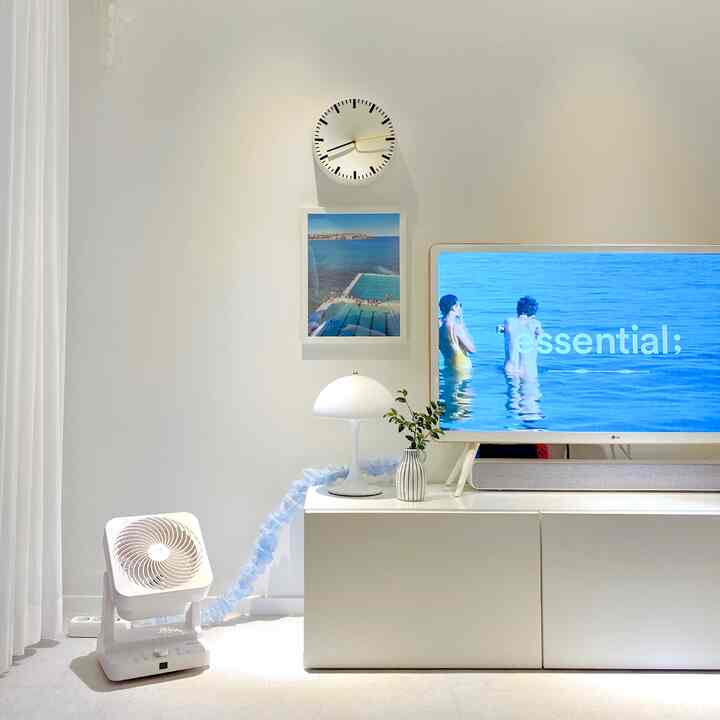 ホワイトトーンのリビング、テレビ台とテーブルランプ、サーキュレーターがあるシンプルでミニマルな雰囲気のインテリア