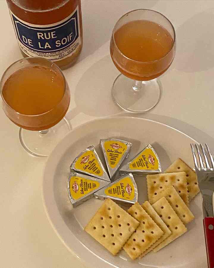 Warm brown and white toned home bar setting featuring wine glasses, cheese wedges, and crackers arranged on a table