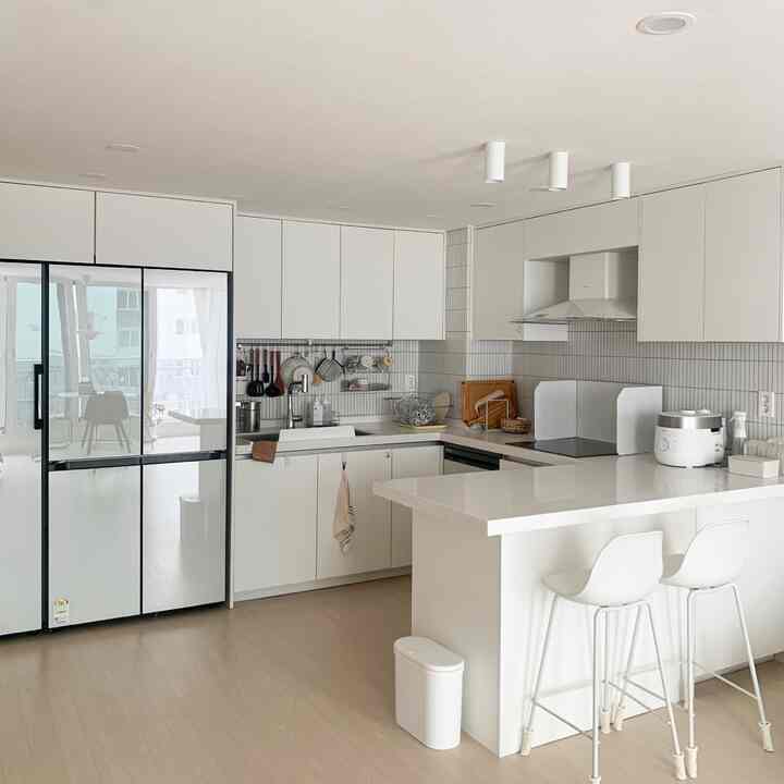 White-toned kitchen space featuring clean storage, built-in ceiling lights, and a simple minimalist design