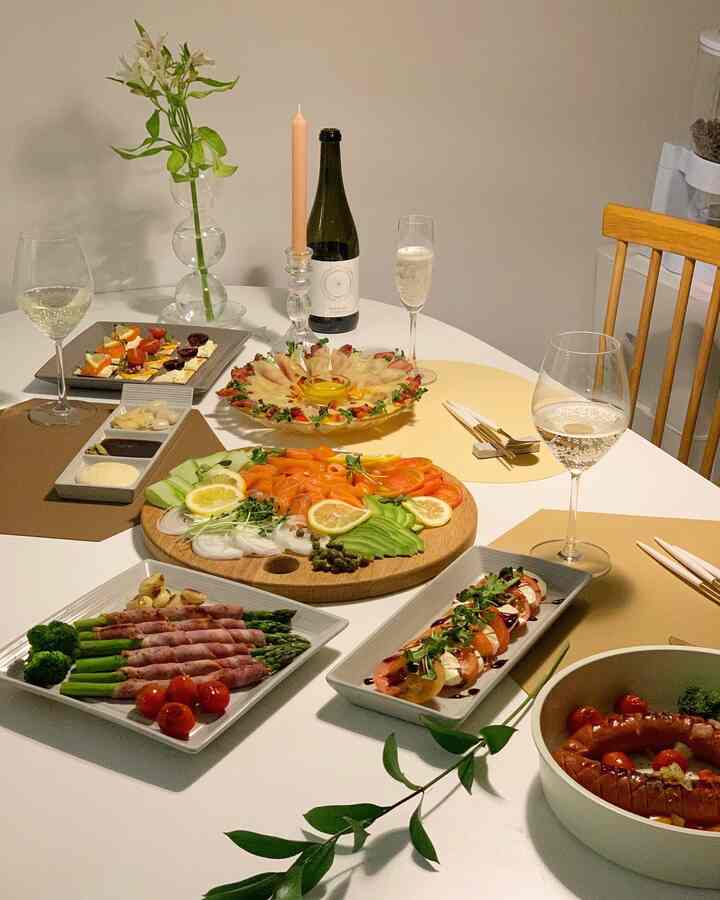 ホワイトと木目調が調和するキッチンダイニングテーブル、料理とワイングラスが並ぶ雰囲気のあるホームパーティー空間