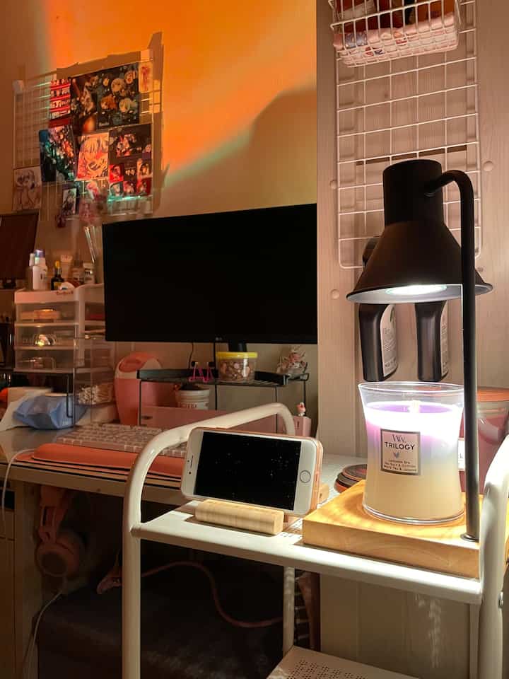 Cozy small room with computer desk and candle illuminated by warm orange lighting