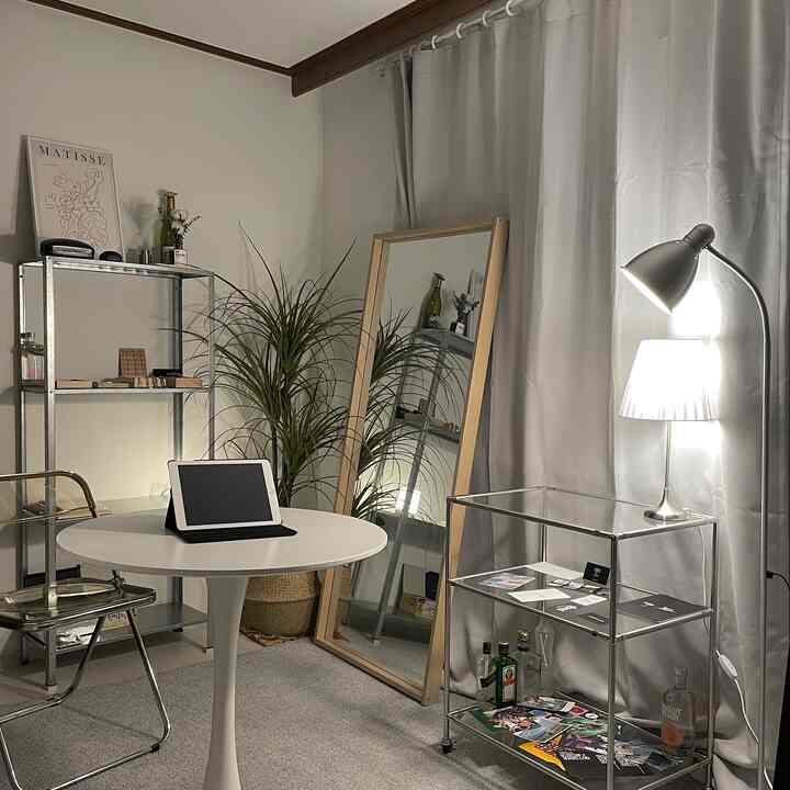 White and silver toned round room home office space featuring a round table and metal shelving with a simple modern interior