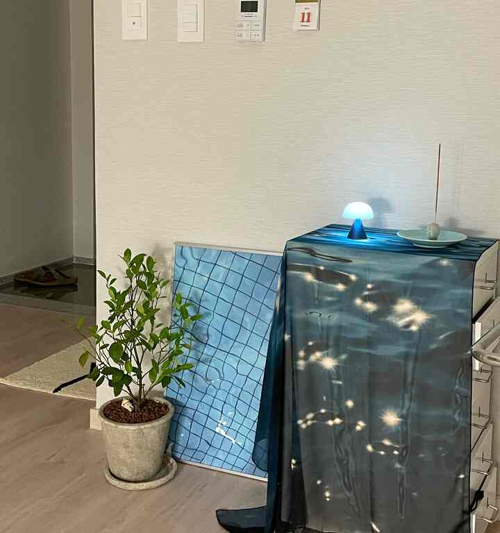 Natural color room with beige walls and flooring featuring a potted plant and white metal drawer with a blue LED mini mushroom lamp, in a minimalist setting