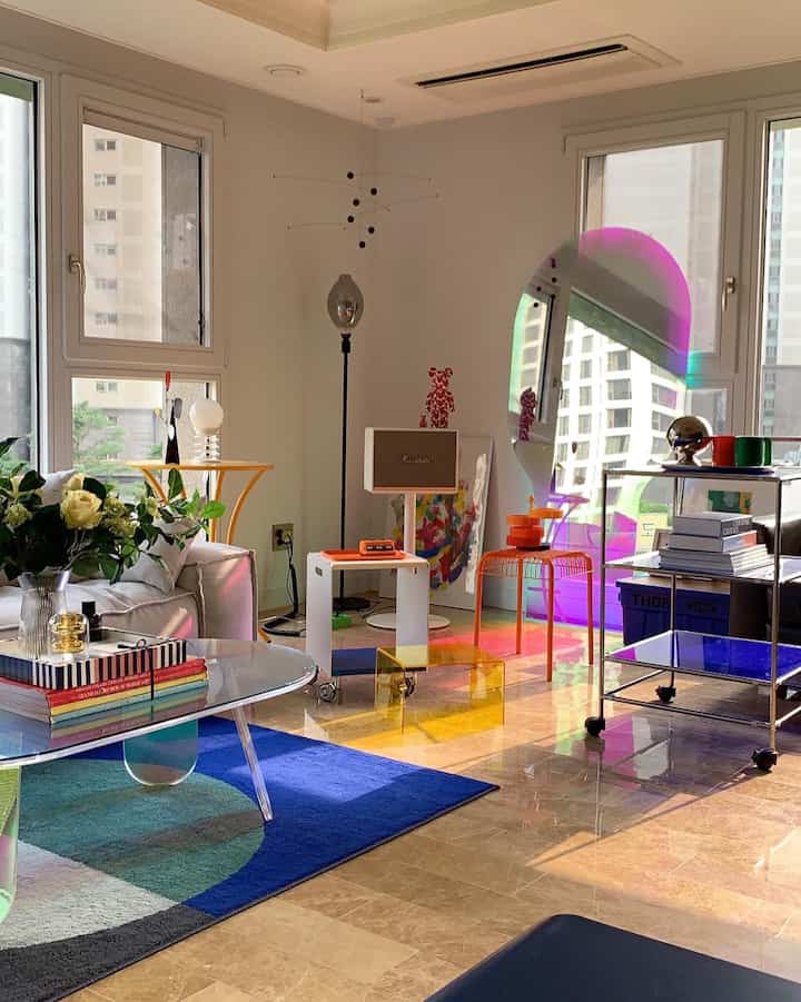 Bright blue-toned rug and orange furniture harmonize in a sunlit modern living room