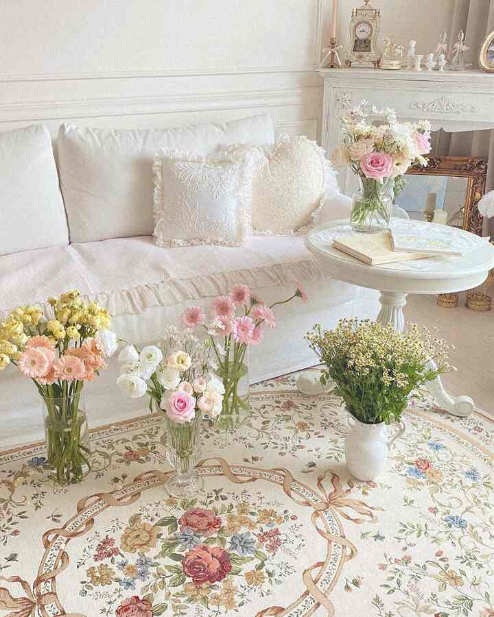 White and vintage-toned living room featuring floral rug and vases with fresh flowers, classic and cozy interior design